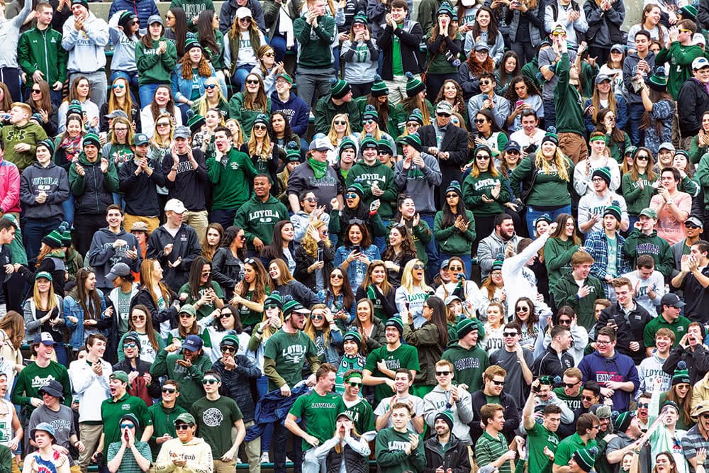 A large crowd at an athletics game - many wearing green, white, and grey shirts