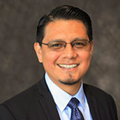 Milton Javier Bravo smiling and wearing a suit
