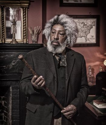 man in period costume in an office holding a stick