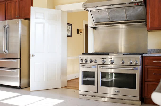 A kitchen with a stainless steel stovetop, oven, and refrigerator