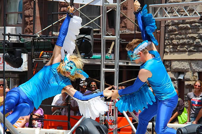 Entertainers wearing blue bird costumes and swinging on ropes