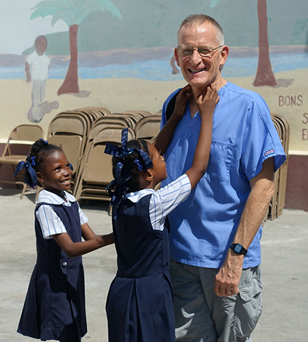 Haitian girls in school uniforms smile and laugh with the dentist.
