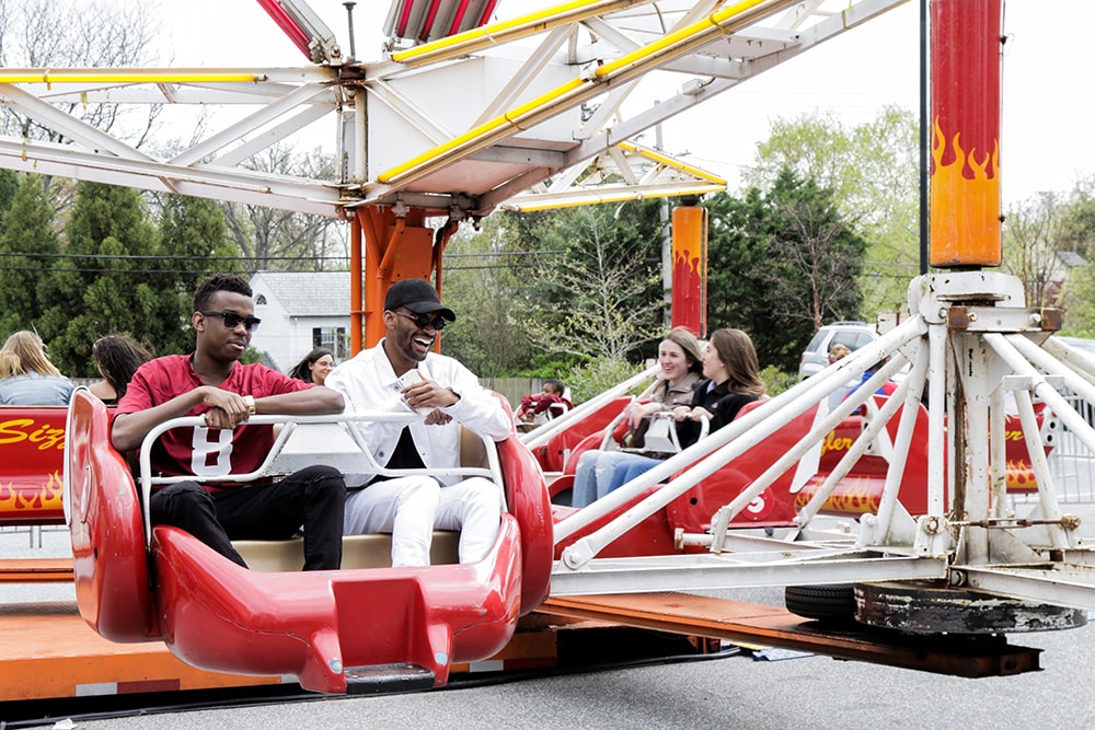 Students laughing and riding on an amusement ride at Loyolapalooza