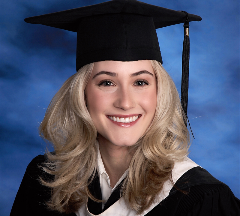 Lily Tiger smiles in cap and gown with blue background