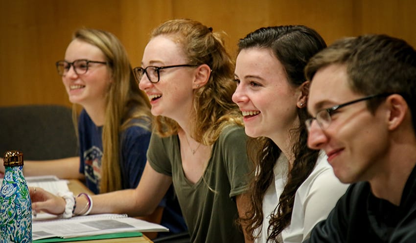 A row of students smiling while sitting at a table
