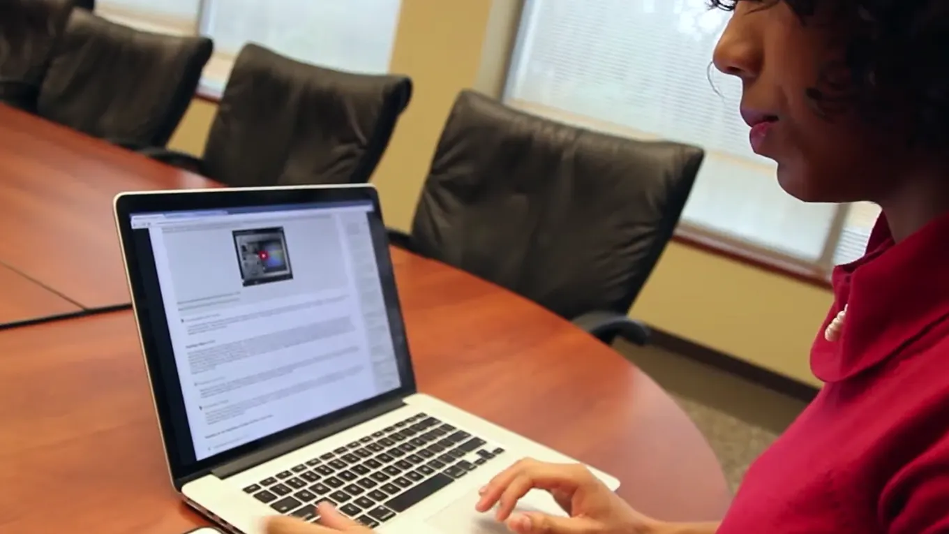 A student using a laptop at a conference table - Press enter to play