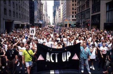 a crowd of people in a protest holding an Act Up banner