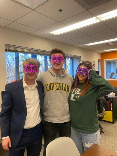students posing and smiling at camera wearing bright purple masks
