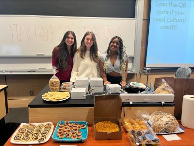 students posing and smiling in front of a table full of baked goods