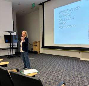 Giuliana Risso-Robberto standing in front of a large projection screen