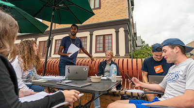 Students prepping for a group project at an outdoor patio table on a nice day