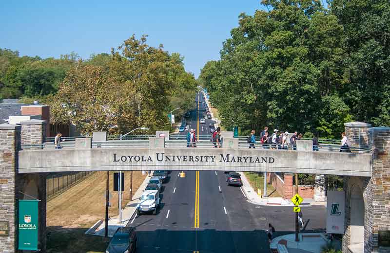 Stone pedestrian bridge over Charles Street, connecting two sides of campus, as groups of students walk across