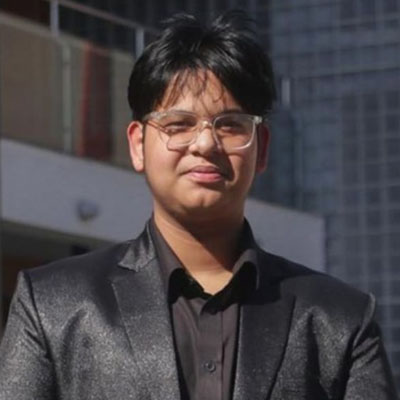 Yukesh smiling in an ornate black suit