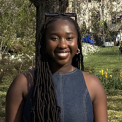 Keli smiling in a large garden full of blooming flowers