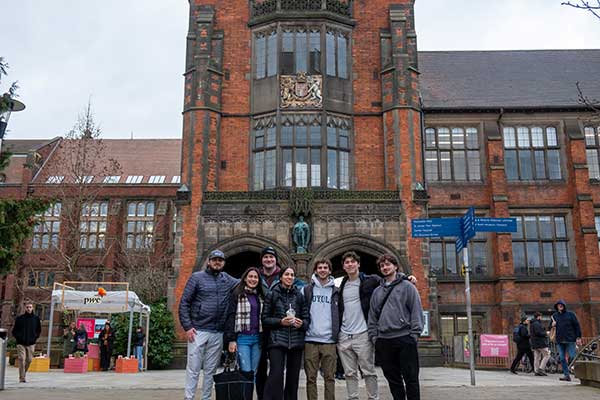 Group of students posing for a photo in front of an old brick building