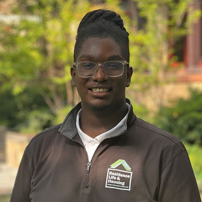 Devin Jenkins-Drumgold smiling in a Loyola Resident Assistant quarter zip shirt