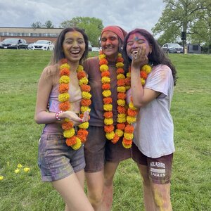 Three students covered in paint, celebrating Holi
