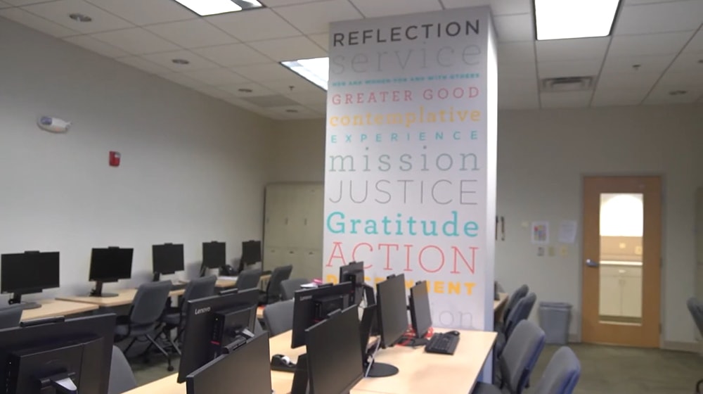 A computer lab with colorful text written on a column in the middle of the room - Press enter to play