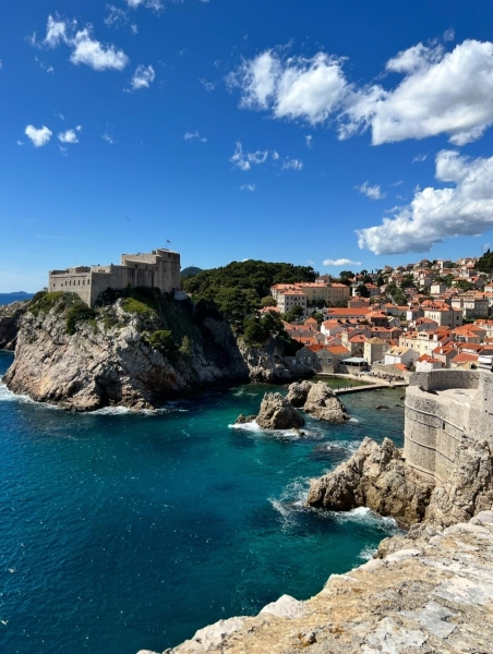 Dubrovnik west harbor, deep blue ocean with medieval walls and houses with orange roofs surrounding it.