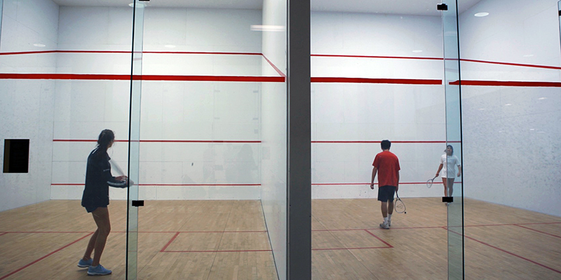 Students playing racquetball in two side-by-side courts
