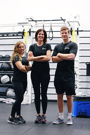 Three personal trainers smiling with their arms crossed