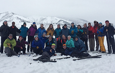 Large group posing in front of very snowy mountains on a ski trip
