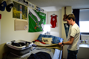 Student folding clothes and organizing belongings in his dorm room