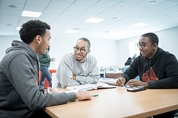 Three male students having a conversation at table