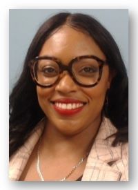 Nikia smiling with glasses, red lipstick and a blazer