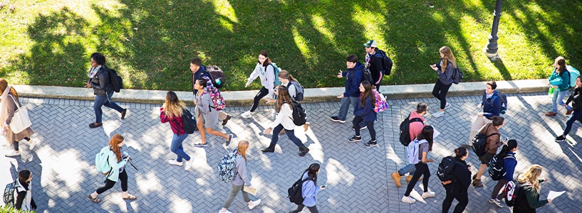 Aerial view of many students walking along a pathway on campus