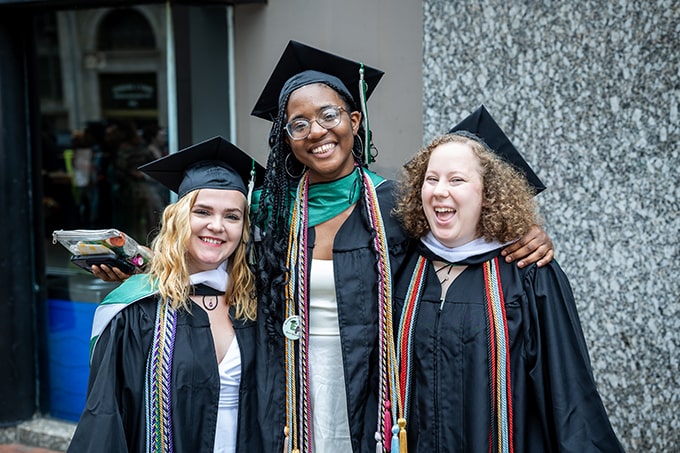 Three graduates of the Class of 2024 smile and pose for a photo