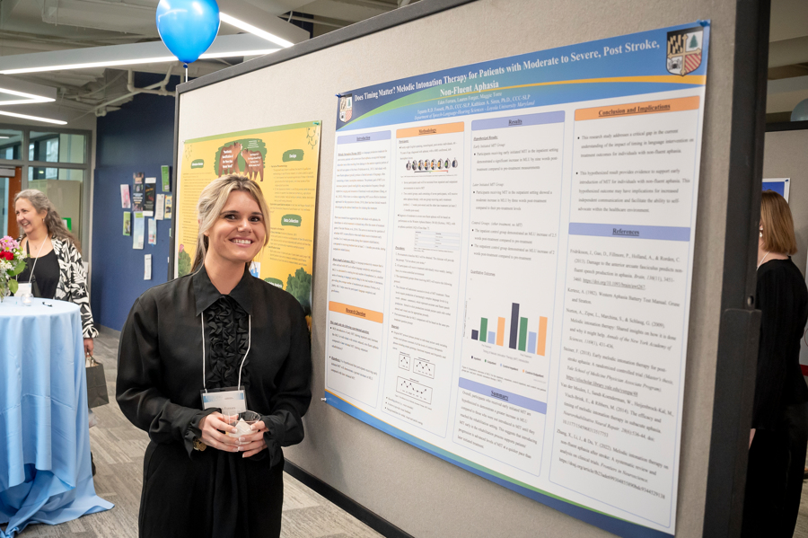 Graduate student in Speech and Hearing Sciences smiles in front of her poster at Emering Scholars 2024