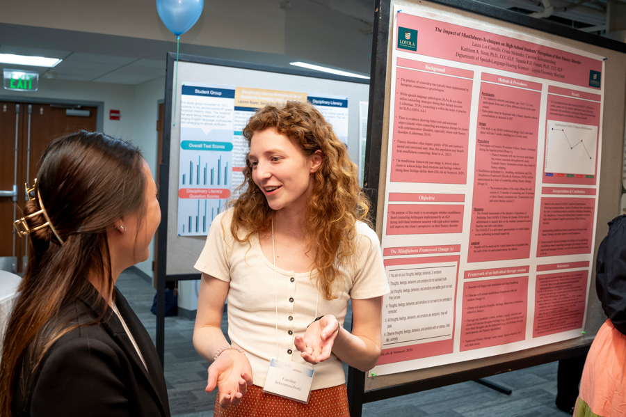Graduate student discusses her research with visitor at Emerging Scholars 2024