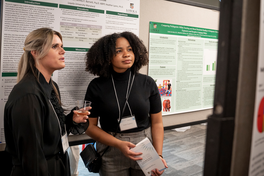 Two graduate students examine research poster at Emerging Scholars Loyola University Maryland