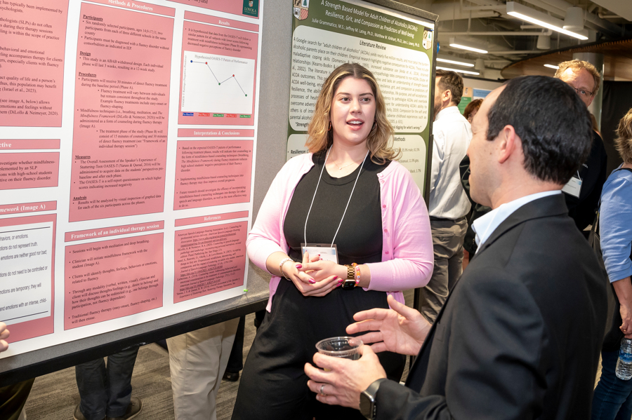 Presenter discusses research poster with visitor at Emerging Scholars 2024
