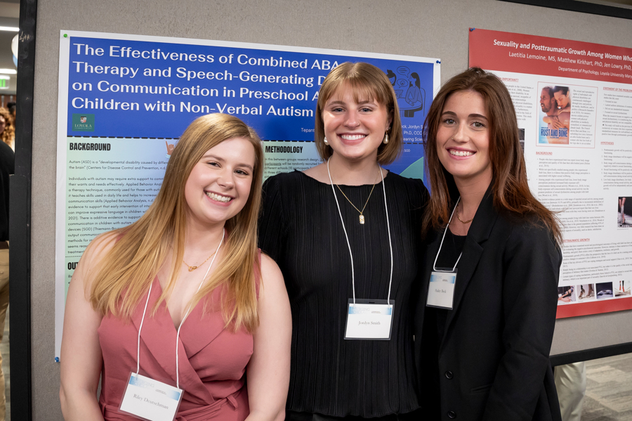 Group of three graduate student presenters smile in front of poster at Emerging Scholars 2024