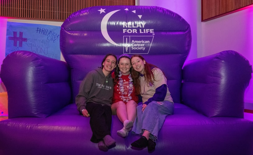 Three female students sitting on an oversized purple blow-up couch