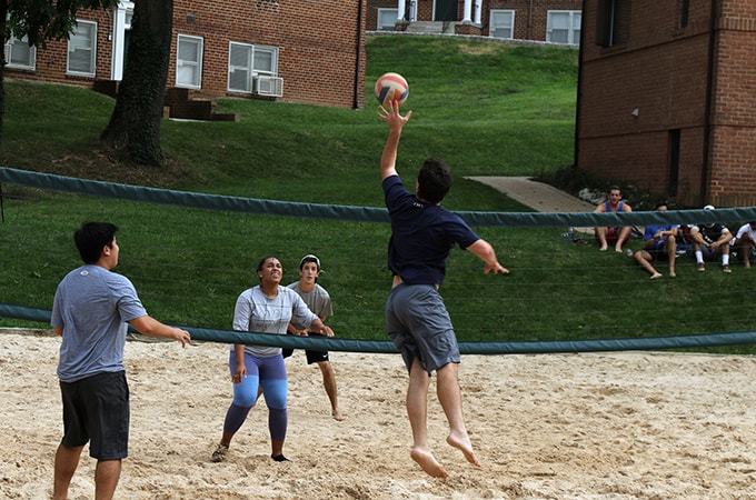 Students playing volleyball on the sand on Loyola's campus