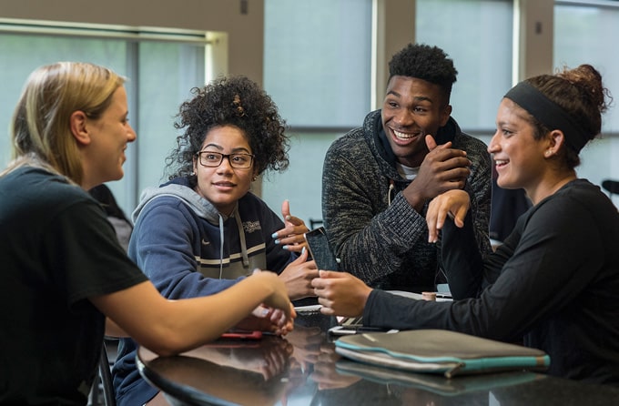 Group of students laugh together in a residence hall.