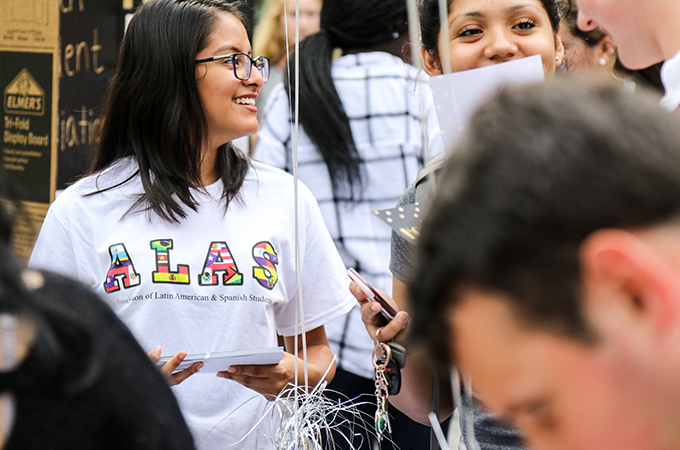 A student advertises for an ALANA club at the student activities fair.