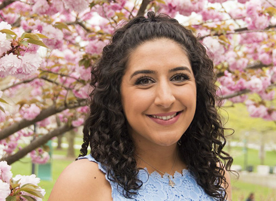 Sandy Abboud smiles, surrounded by cherry blossoms.