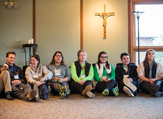 Students sit against the wall, beneath a crucifix at the retreat house.