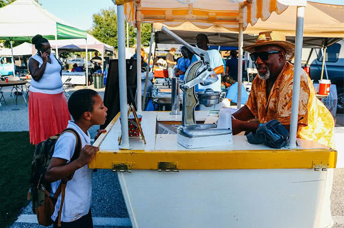 A young child looks at information at a food stand at the farmer's market
