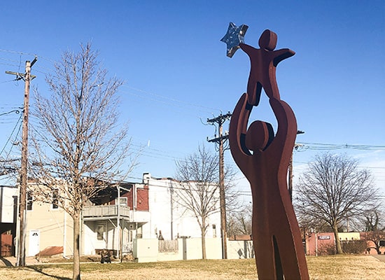 Sculpture of a parent lifting a child in the air in a Baltimore neighborhood