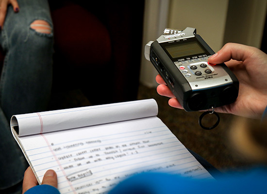 A student holding a voice recorder and notepad