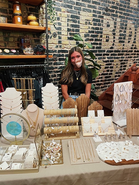 Maria Jaeckel sits at a table displaying her jewelry in a pop-up shop