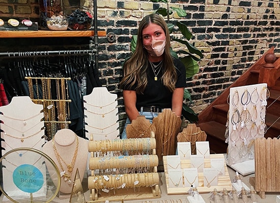 Maria Jaeckel sits at a table displaying her jewelry in a pop-up shop