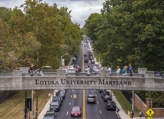Students walk across the Charles St pedestrian bridge on Loyola's Evergreen Campus