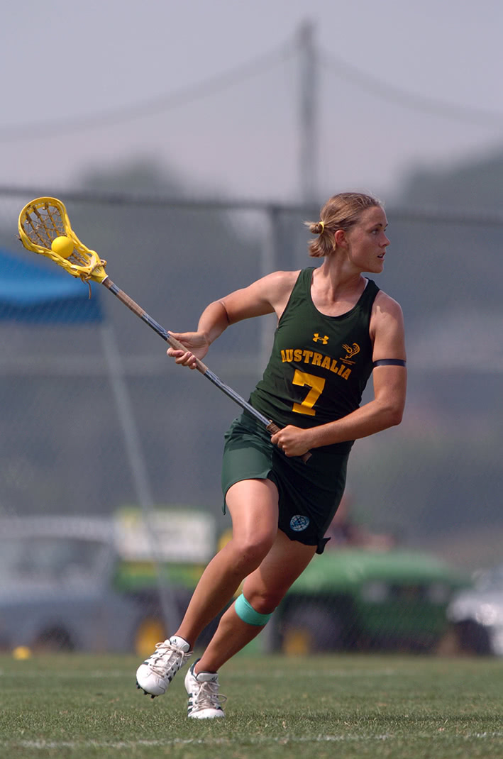 Jen Adams playing lacrosse wearing a green and yellow uniform that says 'Australia' on the front