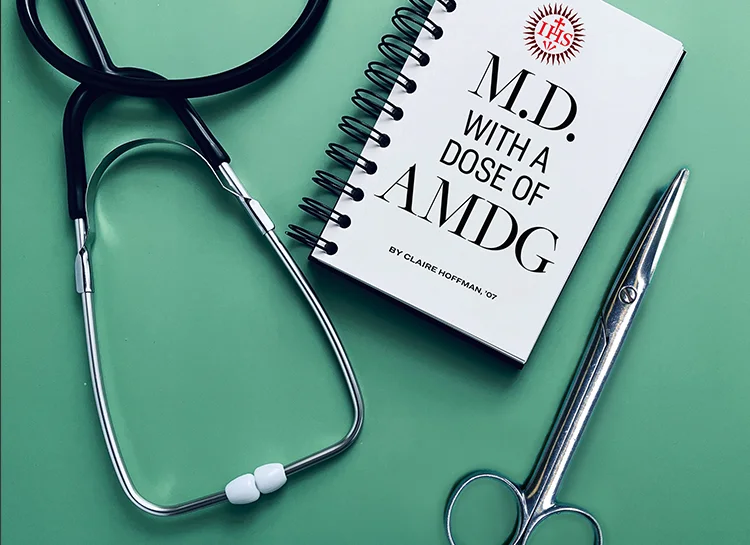 A stethoscope, scissors, and notebook with the words M.D. with a dose of AMDG